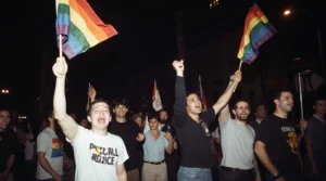 LGBTQ+ activists waving rainbow flags during the Stonewall Riots protest in New York City, 1969